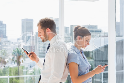 Business team standing back to back and texting