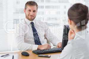 Businessman sitting with a co worker at his desk