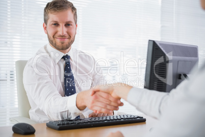 Smiling businessman shaking hands with a co worker and looking a