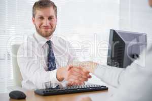 Smiling businessman shaking hands with a co worker and looking a