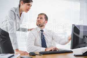 Businessman showing his co worker something on computer