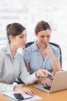 Happy businesswomen working together on a laptop