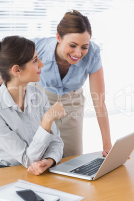 Smiling businesswomen working together with laptop