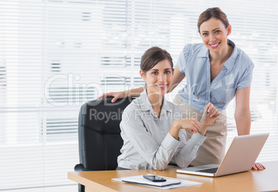 Businesswomen at desk smiling at camera