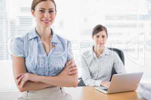 Happy businesswomen smiling at camera at their desk