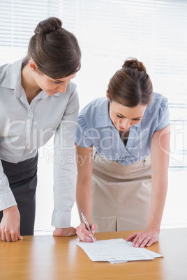 Businesswomen leaning on desk looking at paperwork