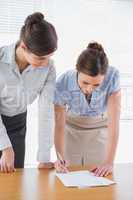 Businesswomen leaning on desk looking at paperwork