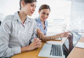 Businesswoman pointing something out on laptop for colleague