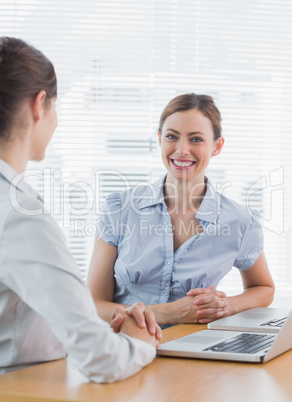 Attractive businesswoman smiling at camera with her colleague