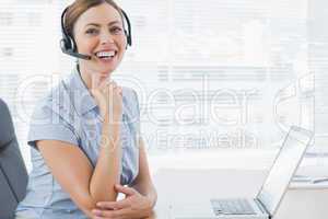 Laughing call centre agent wearing headset at her desk