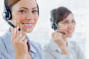 Smiling call centre agents with headsets at work
