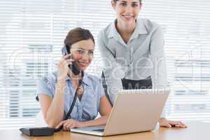 Businesswoman calling and smiling at camera with co worker