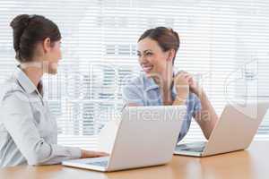 Businesswoman laughing together at desk