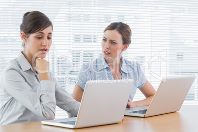 Worried businesswomen working on laptops