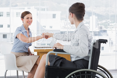 Businesswoman shaking hands with disabled colleague