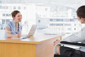 Businesswoman smiling at disabled job candidate