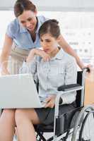 Disabled businesswoman showing colleague her laptop