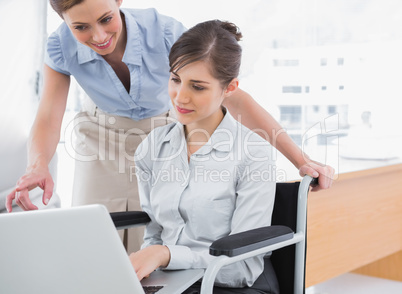 Disabled businesswoman showing co worker her laptop