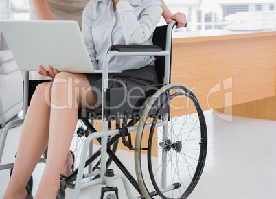 Disabled businesswoman showing laptop to colleague