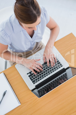 Businesswoman typing on her laptop overhead
