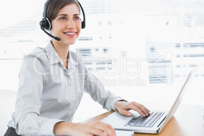 Smiling call centre agent working at desk