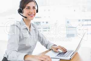 Smiling call centre agent working at desk
