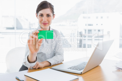 Happy businesswoman showing green business card