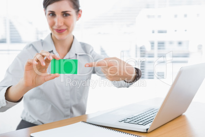 Young businesswoman pointing to green business card
