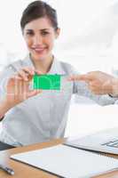 Happy businesswoman pointing to green business card