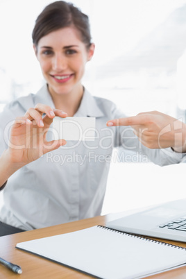 Happy businesswoman pointing to blank business card