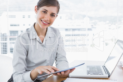 Businesswoman using digital tablet smiling at camera