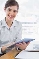 Businesswoman using her digital tablet smiling at camera