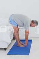 Mature man stretching on an aerobic mat