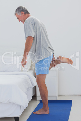 Mature man stretching his leg on an aerobic mat