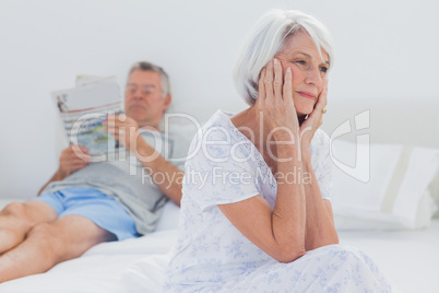 Anxious mature woman sitting on bed