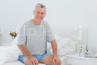 Man smiling while he is sitting on bed