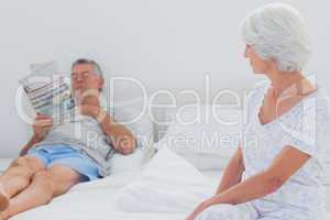Woman looking at husband in the bed