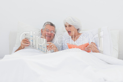 Mature man showing his newspaper to his wife