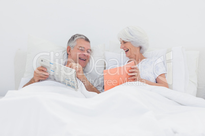 Cheerful woman showing her book to husband