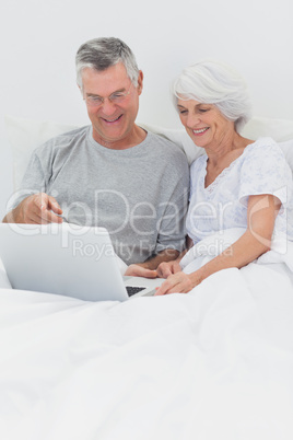 Couple using a laptop together in bed