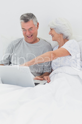Mature woman pointing at husbands laptop