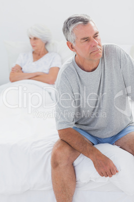 Upset man sitting on bed during a dispute