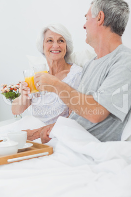 Mature couple clinking their orange juice glasses