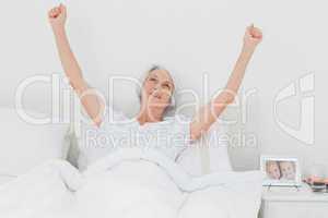 Woman waking up and raising arms in bed
