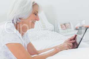 Woman using a tablet while she is lying on bed