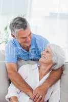 Man hugging wife who is sitting on the couch