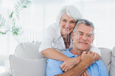 Woman embracing husband sitting on the couch