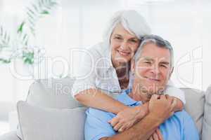 Woman embracing husband sitting on the couch