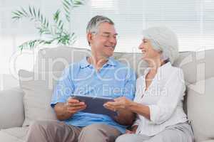 Couple using a tablet pc sitting on the couch