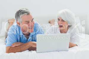 Couple using a laptop in bed